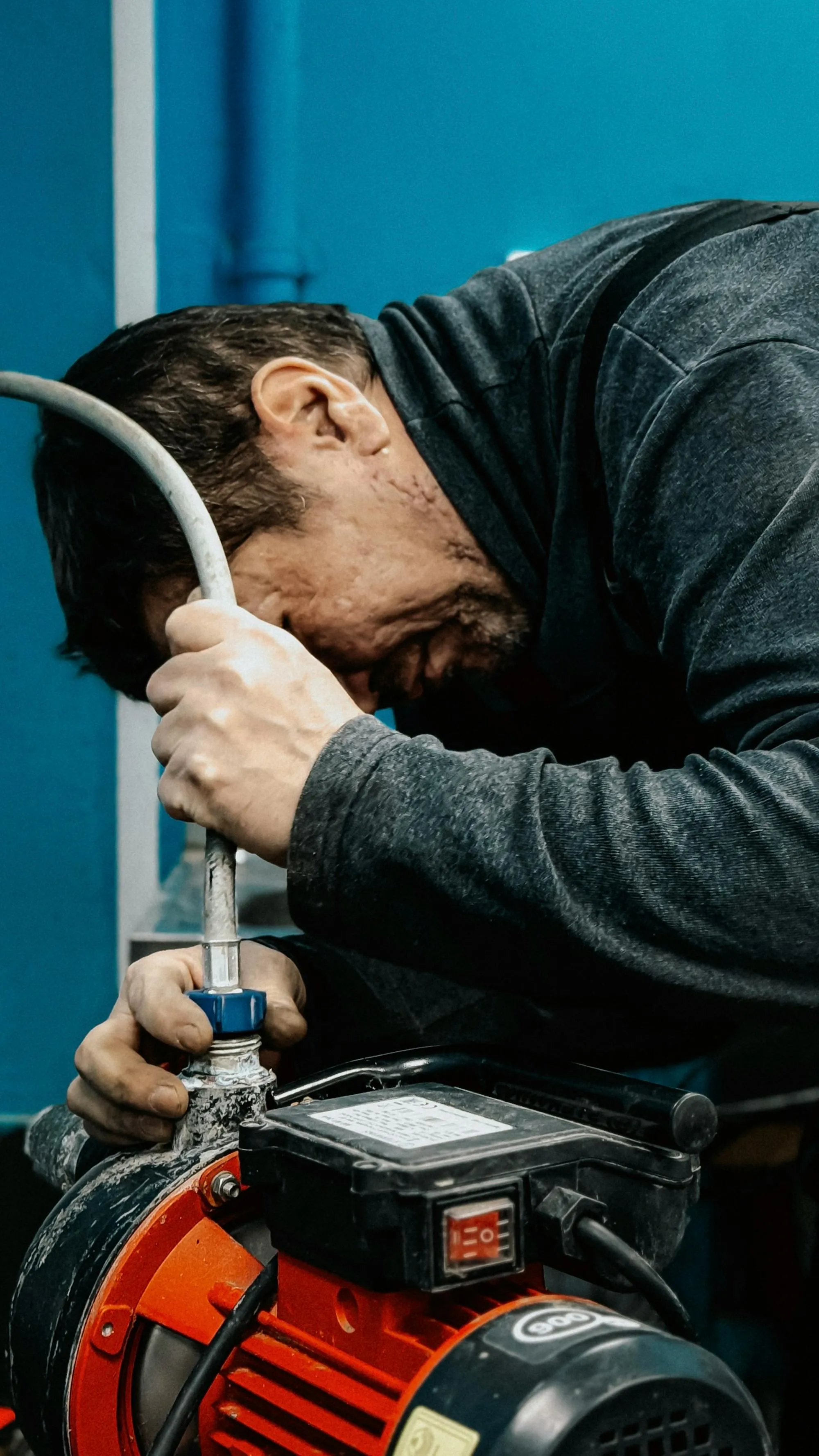 Plumber concentrating on a water pump repair in a workshop